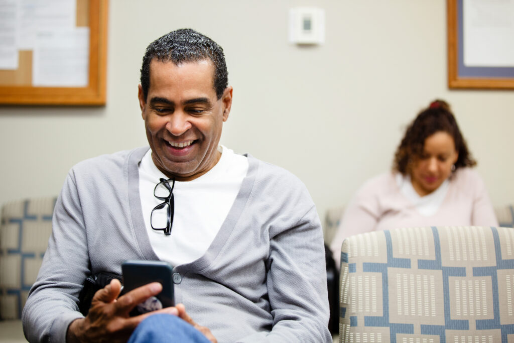 Man uses smartphone while waiting for an appointment in a doctor's office.